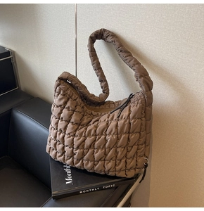 Detailed close-up of brown quilted puffer tote bag resting on a leather sofa