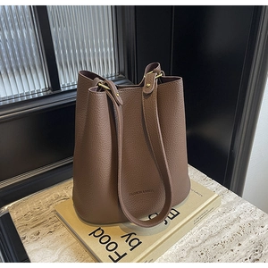 Detail der dunkelbraunen Eimertasche aus Leder mit Fashion & Bags Text auf Steinoberfläche