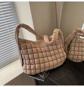 Detail view of the quilted puff tote bag texture and soft beige padded shoulder strap