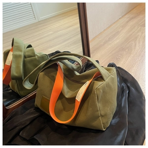 Detail of army green canvas bag with contrasting wide orange strap and stylish woven labels
