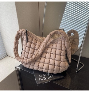 Detailed close-up of quilted puff tote bag in beige with soft texture and metallic zipper
