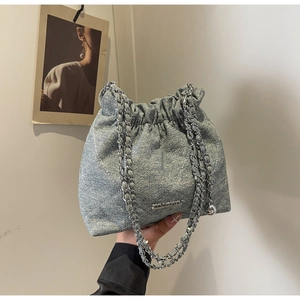 Detail of quilted denim bucket bag with chain strap and metallic ball charm