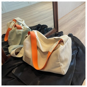 Detail of canvas bag with orange shoulder strap and embossed leather brand logo