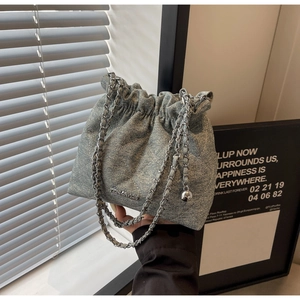 Close-up of light blue denim bucket bag with quilted patterns and drawstring chain strap