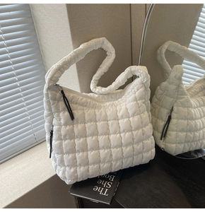 Detail of white puffer tote bag showing quilted texture, zipper closure and padded shoulder strap