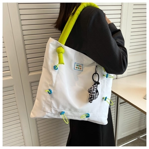 Close-up of white tote bag with neon straps, blue label and checkered heart charm