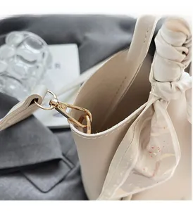 Close-up of beige bucket bag with polished gold hardware and floral scarf detail