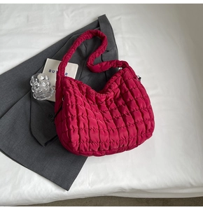 Close-up of bright red quilted bubble tote bag featuring soft puffer texture and wide strap