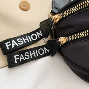 Detail of golden metal zippers with woven fashion pullers on camouflage crossbody bag