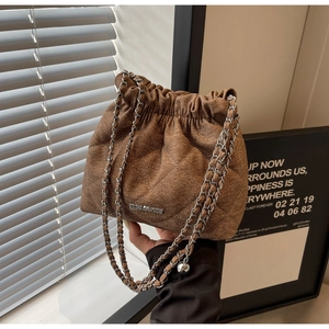 Detail of dark brown quilted bucket bag with silver chain strap and drawstring closure