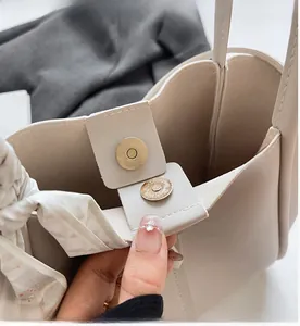 Close-up of beige tote bag with gold magnetic buckle and stylish silk scarf on handle