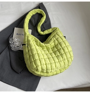 Detail of neon green quilted tote bag with puffer texture on a grey suit background