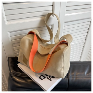 Detail of khaki canvas tote bag featuring vibrant orange wide strap on a sofa
