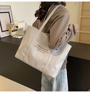 Close-up of durable canvas tote bag with letter print and wide shoulder strap
