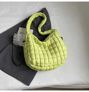 Flat lay of neon green quilted puffer tote bag with wide strap on minimalist background