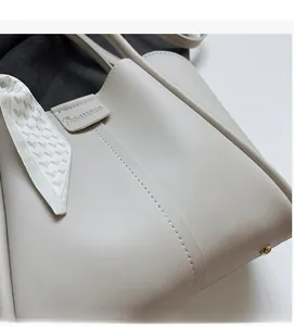 Detailed macro view of beige leather handbag texture with decorative silk scarf handle