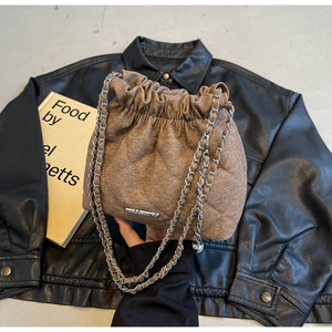Detail of a brown quilted bucket bag with silver chain and drawstring closure