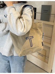 Khaki canvas tote bag with large blue embroidered T for daily commute and school