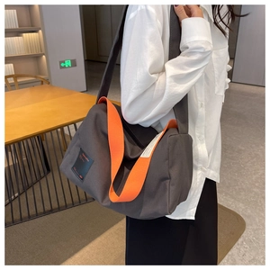 Detail of grey canvas crossbody bag with vibrant orange strap for daily use