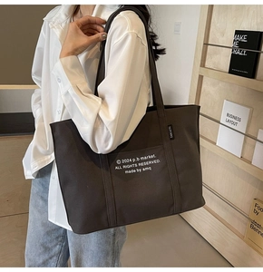 Close-up of charcoal canvas tote bag featuring wide straps and white printed lettering