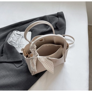 Detail of beige bucket bag with decorative silk scarf and matching inner pouch