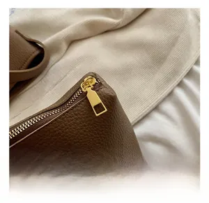 Close-up of premium gold zipper hardware on brown litchi pattern leather bag detail