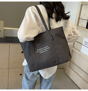Detail of dark grey canvas tote bag with front pocket and white graphic print