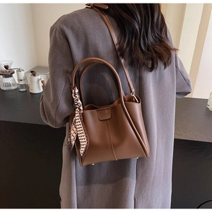Brown litchi grain leather bucket bag with heart print silk scarf on a model