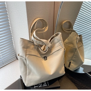 Detail of canvas tote bag with side pockets and adjustable strap shown in mirror reflection