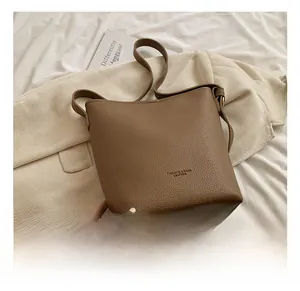 Detailed view of brown lychee grain leather bucket bag with soft shoulder strap and lettering