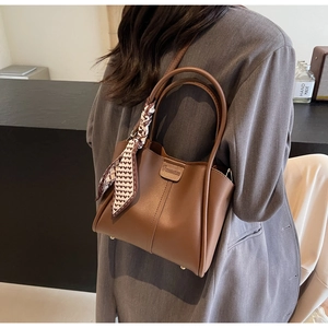 Brown leather bucket bag with geometric silk scarf detail and adjustable strap
