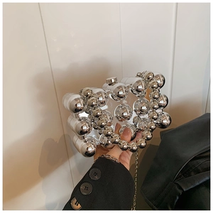 Macro detail of silver acrylic evening bag with 3D mirror spheres and metal chain