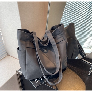 Detail of grey canvas tote bag featuring silver metal twist lock and side storage pocket