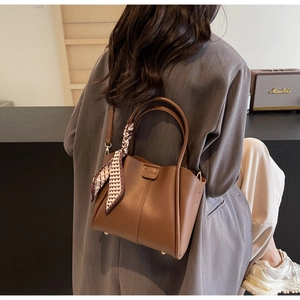 Detail of vintage brown bucket bag with heart print scarf accent on handle