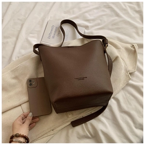 Detail of dark brown lychee leather bucket bag with wide strap and matching accessories
