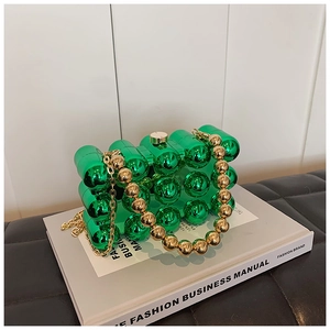Detailed macro view of green acrylic evening bag featuring gold beaded handle and metal chain