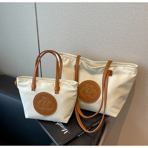 Detalle del juego de bolsos tote blanco roto con asas de cuero marrón y logo bordado