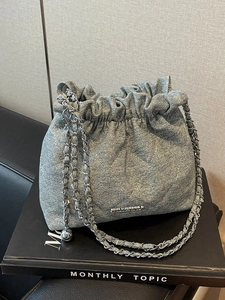 Quilted denim bucket bag with chain strap and metallic charm details for women