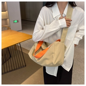 Detail of khaki canvas crossbody bag with orange handles and wide shoulder strap