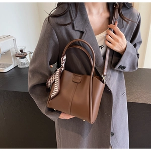 Detail of a brown vintage leather handbag with a decorative geometric silk scarf handle