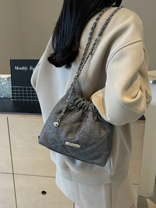 Gray quilted bucket bag with silver chain strap and drawstring closure for women
