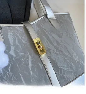 Detail of silver tote bag showing crinkled metallic texture and gold turn-lock closure