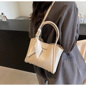 Detail of off-white leather bucket bag with decorative checkered scarf and embossed logo