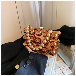 Detail of rose gold acrylic evening bag with stacked spherical design and beaded handle