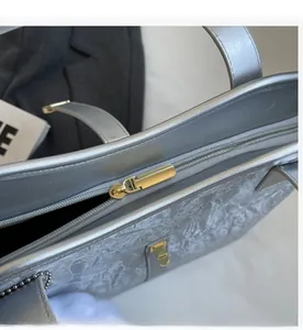Close-up of golden zipper and textured silver metallic tote bag with smooth closure