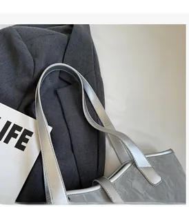 Macro detail of silver tote bag with metallic crinkle texture and smooth handle