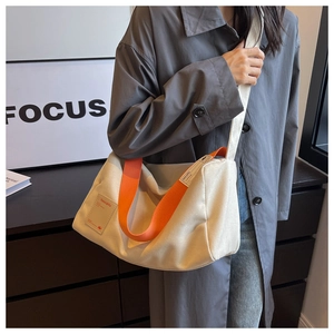 Close-up of canvas pillow bag featuring vibrant orange straps and trend design label