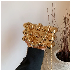 Detail of gold acrylic evening bag with 3D beaded texture and detachable chain