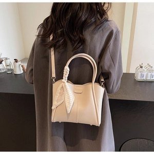 Detail of cream crossbody bucket bag with checkered silk scarf and detachable strap