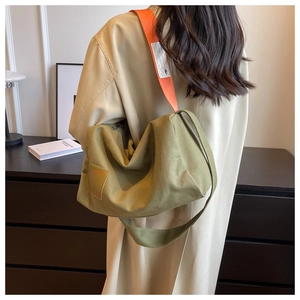 Detail of army green canvas hobo bag with contrast orange shoulder strap on model
